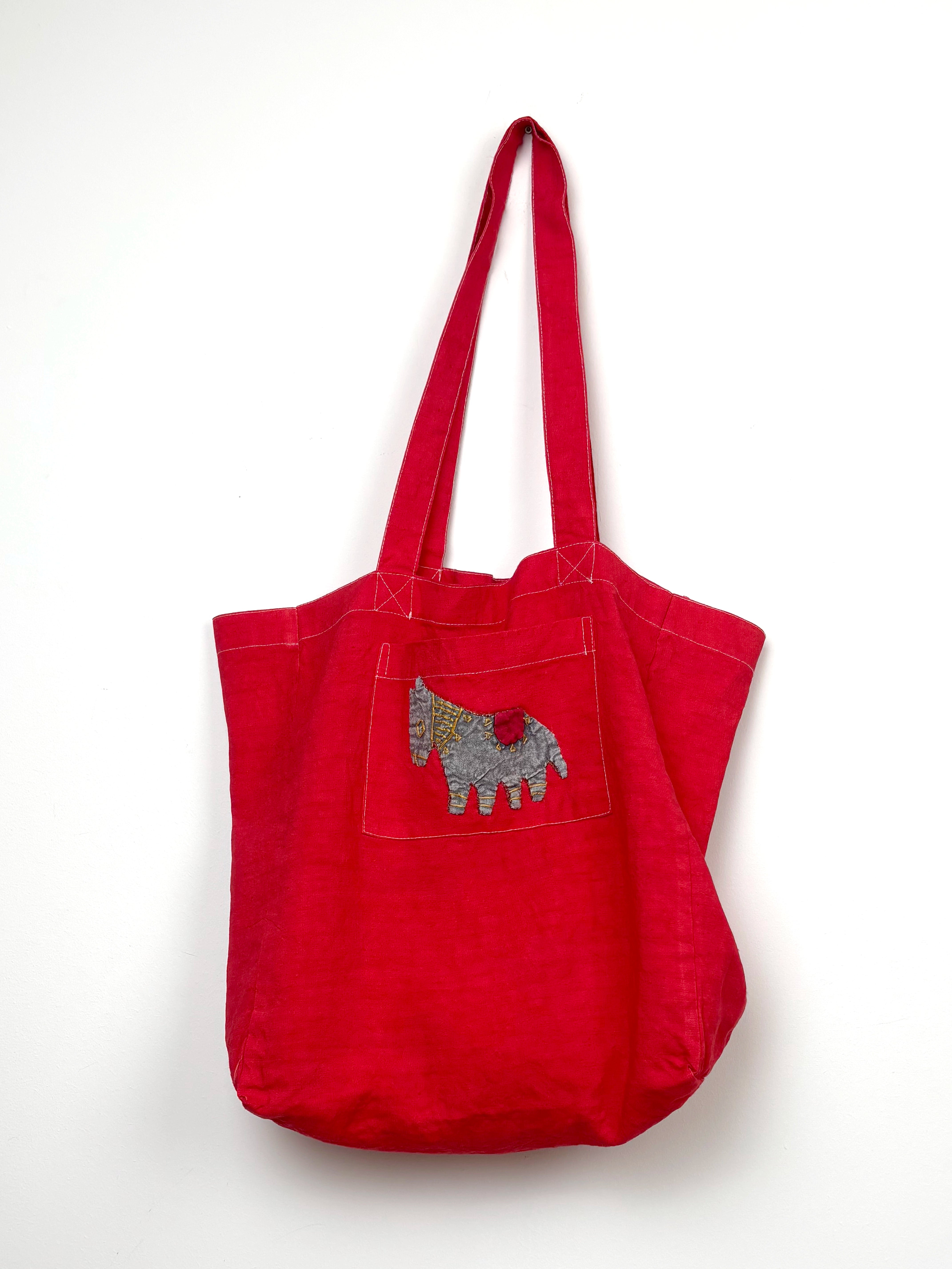 Grey horse in a red dyed bag